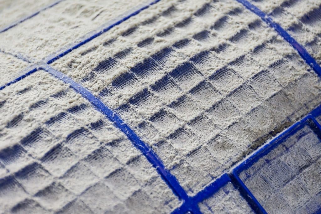 Close-up of a heavily dust-covered HVAC air filter with clogged blue grid panels.